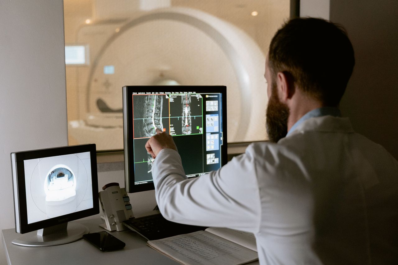 Offerings Medical professional reviewing MRI scans on computer screens for diagnostic purposes.