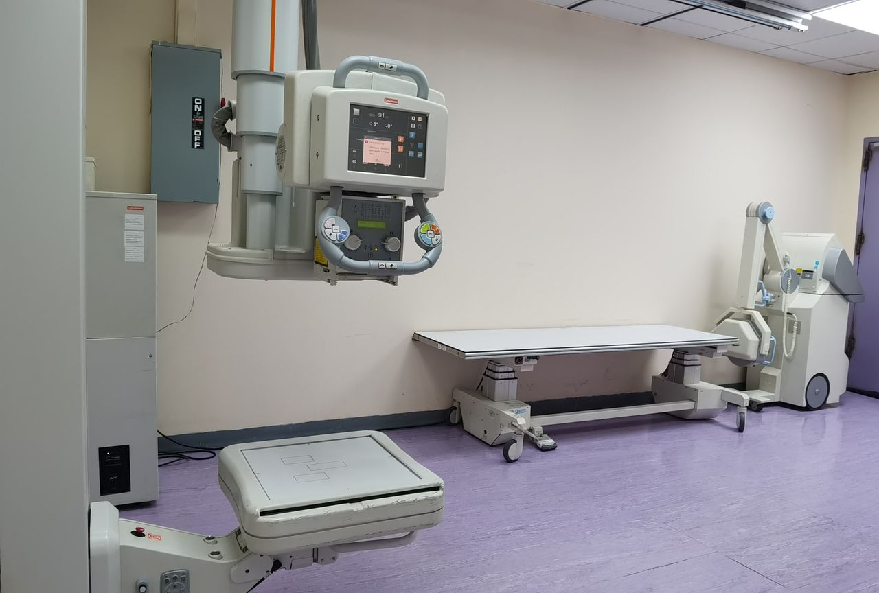Offerings Clinical setting with X-ray machines and examination table in a healthcare facility.